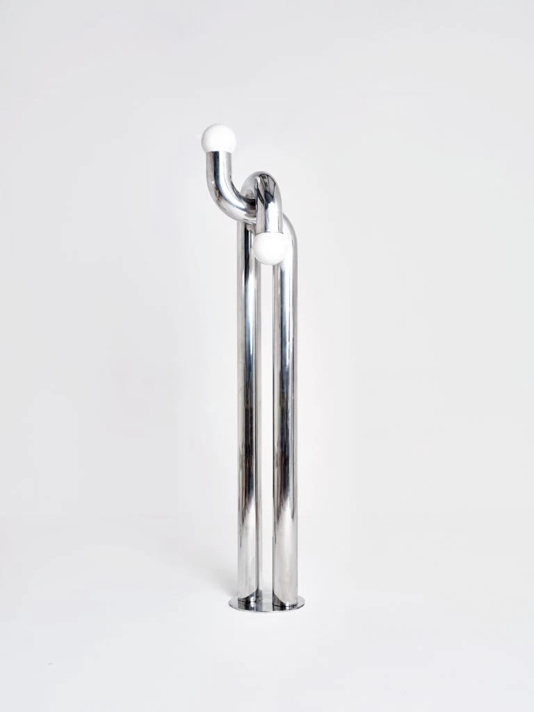 Sculpture en aluminium poli d'Axel Chay présentée dans un environnement minimaliste argenté.